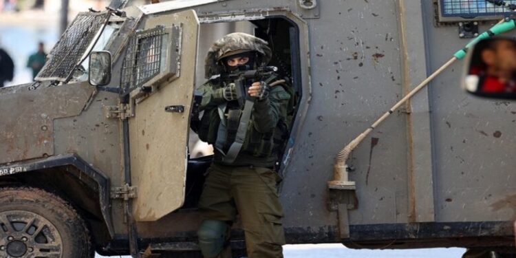 An Israeli soldier gestures on December 13, 2023 following an overnight army raid in Jenin in the occupied West Bank, as battles continue between Israel and the militant movement Hamas in Gaza. Israeli forces killed four Palestinians in Jenin on December 12, the Palestinian health ministry reported without further details on the fatalities, while the Palestinian Red Crescent Society said they were killed in a drone strike in the old town. (Photo by Jaafar ASHTIYEH / AFP)