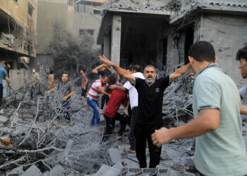 A Palestinian men react while a wounded girl is rescued from the rubble of a house after it was hit by Israeli strikes, in Khan Younis in the southern Gaza Strip, October 14, 2023. REUTERS/Yasser Qudih