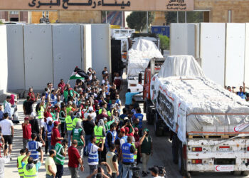Egyptian volunteers gather and celebrate with a Palestinian flag next to trucks carrying humanitarian aid from Egyptian NGOs driving through the Rafah crossing from the Egyptian side, amid the ongoing conflict between Israel and the Palestinian Islamist group Hamas, in Rafah, Egypt October 21, 2023. REUTERS/Stringer      TPX IMAGES OF THE DAY