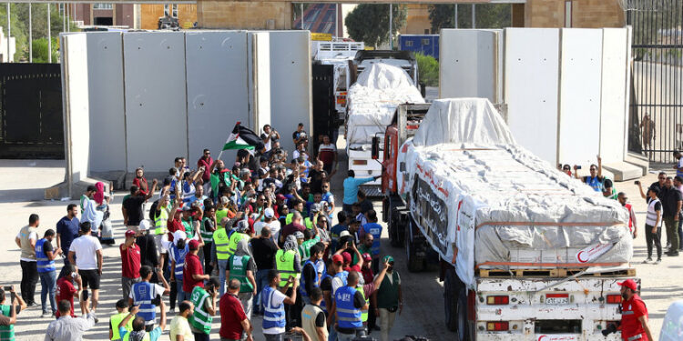 Egyptian volunteers gather and celebrate with a Palestinian flag next to trucks carrying humanitarian aid from Egyptian NGOs driving through the Rafah crossing from the Egyptian side, amid the ongoing conflict between Israel and the Palestinian Islamist group Hamas, in Rafah, Egypt October 21, 2023. REUTERS/Stringer      TPX IMAGES OF THE DAY