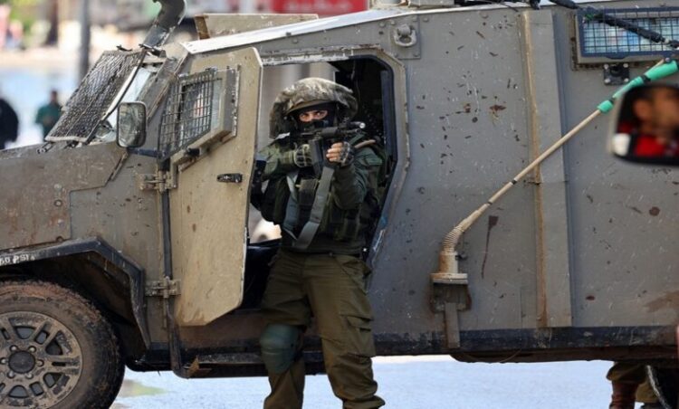 An Israeli soldier gestures on December 13, 2023 following an overnight army raid in Jenin in the occupied West Bank, as battles continue between Israel and the militant movement Hamas in Gaza. Israeli forces killed four Palestinians in Jenin on December 12, the Palestinian health ministry reported without further details on the fatalities, while the Palestinian Red Crescent Society said they were killed in a drone strike in the old town. (Photo by Jaafar ASHTIYEH / AFP)