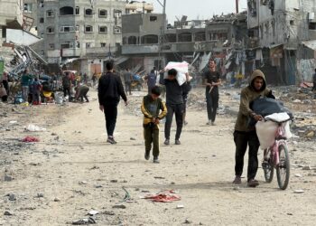 Palestinians walk past houses damaged by Israeli strikes during the conflict, amid a temporary truce between Israel and Hamas, in the northern Gaza Strip, November 25, 2023. REUTERS/Abed Sabah 