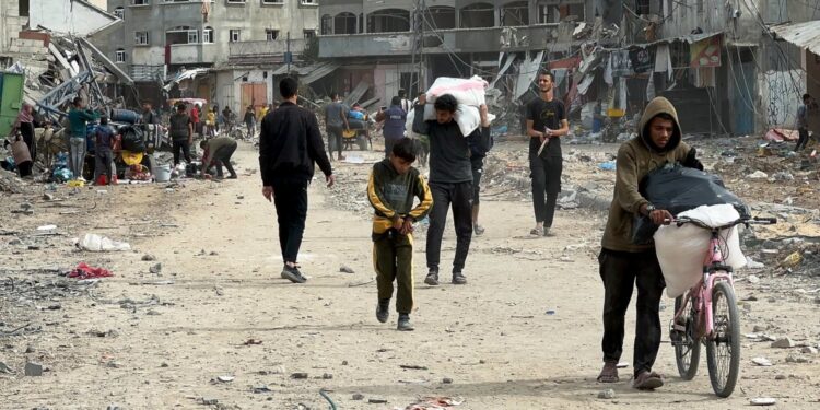 Palestinians walk past houses damaged by Israeli strikes during the conflict, amid a temporary truce between Israel and Hamas, in the northern Gaza Strip, November 25, 2023. REUTERS/Abed Sabah 