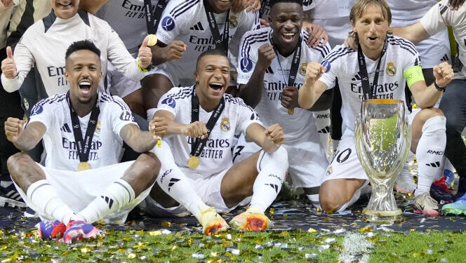 Real Madrid's Eder Militao, Kylian Mbappe, Vinicius Junior, and Luka Modric pose with the trophy after winning the UEFA Super Cup Final soccer match between Real Madrid and Atalanta at the Narodowy stadium in Warsaw, Poland, Wednesday, Aug. 14, 2024. Real Madrid won 2-0. (AP Photo/Darko Bandic)