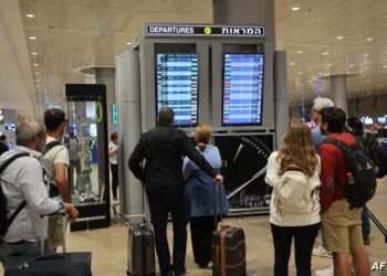 Passengers look at a departure board at Ben Gurion Airport near Tel Aviv, Israel, on October 7, 2023, as flights are canceled because of the Hamas surprise attacks. The conflict sparked major disruption at Tel Aviv airport, with American Airlines, Emirates, Lufthansa and Ryanair among carriers with cancelled flights. (Photo by GIL COHEN-MAGEN / AFP)