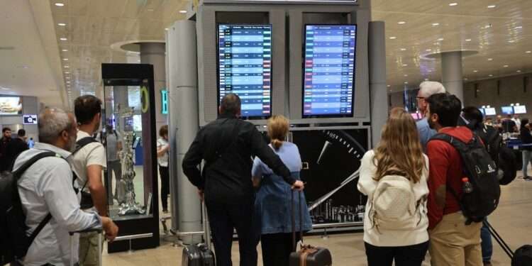 Passengers look at a departure board at Ben Gurion Airport near Tel Aviv, Israel, on October 7, 2023, as flights are canceled because of the Hamas surprise attacks. The conflict sparked major disruption at Tel Aviv airport, with American Airlines, Emirates, Lufthansa and Ryanair among carriers with cancelled flights. (Photo by GIL COHEN-MAGEN / AFP)