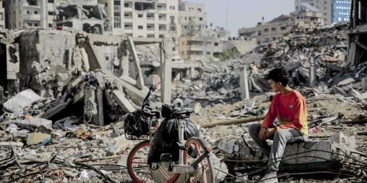 A Palestinian youth sits next to his bicycle amid the rubble of destroyed buildings in Gaza City on the northern Gaza strip following weeks of Israeli bombardment, as a four-day ceasefire took effect on November 24, 2023. The truce in the Israel-Hamas war began on November 24 and appeared to be holding, under a deal that will see hostages released in exchange for Palestinian prisoners. (Photo by AFP)