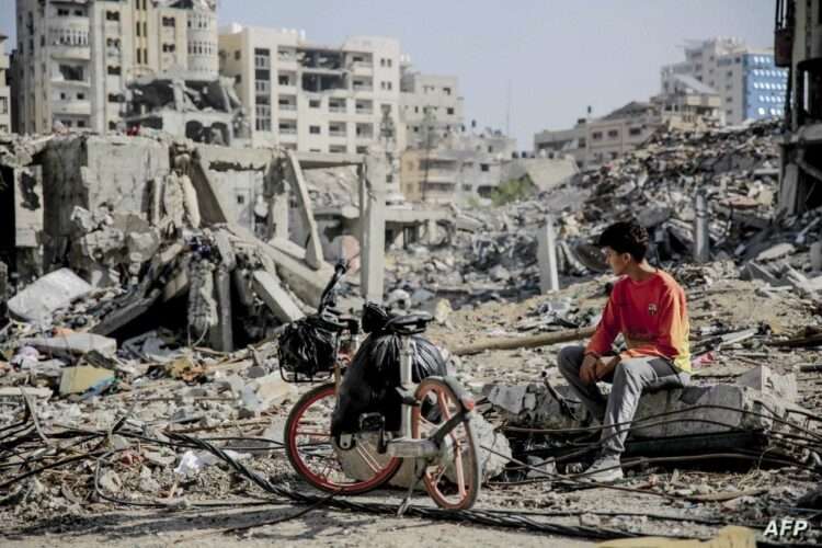 A Palestinian youth sits next to his bicycle amid the rubble of destroyed buildings in Gaza City on the northern Gaza strip following weeks of Israeli bombardment, as a four-day ceasefire took effect on November 24, 2023. The truce in the Israel-Hamas war began on November 24 and appeared to be holding, under a deal that will see hostages released in exchange for Palestinian prisoners. (Photo by AFP)
